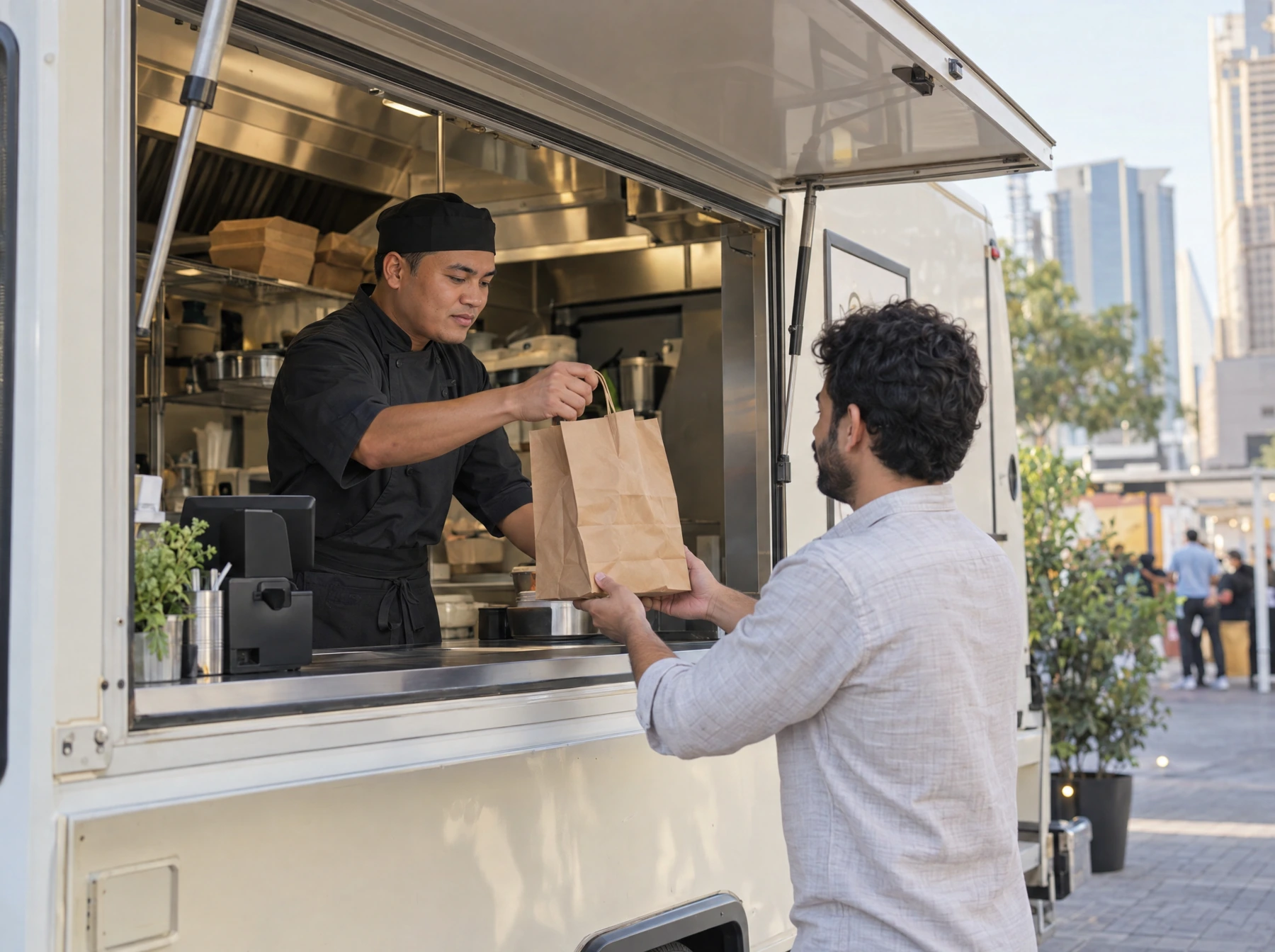 A food-truck team member hands a neatly packed takeaway order to a guest at the service window